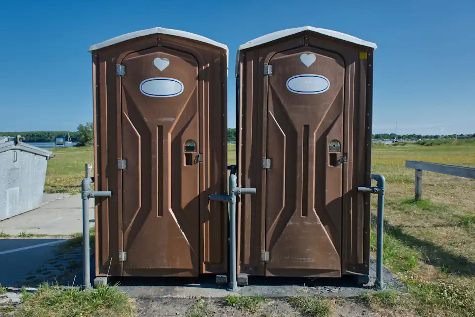 Two brown chemical toilets outdoors