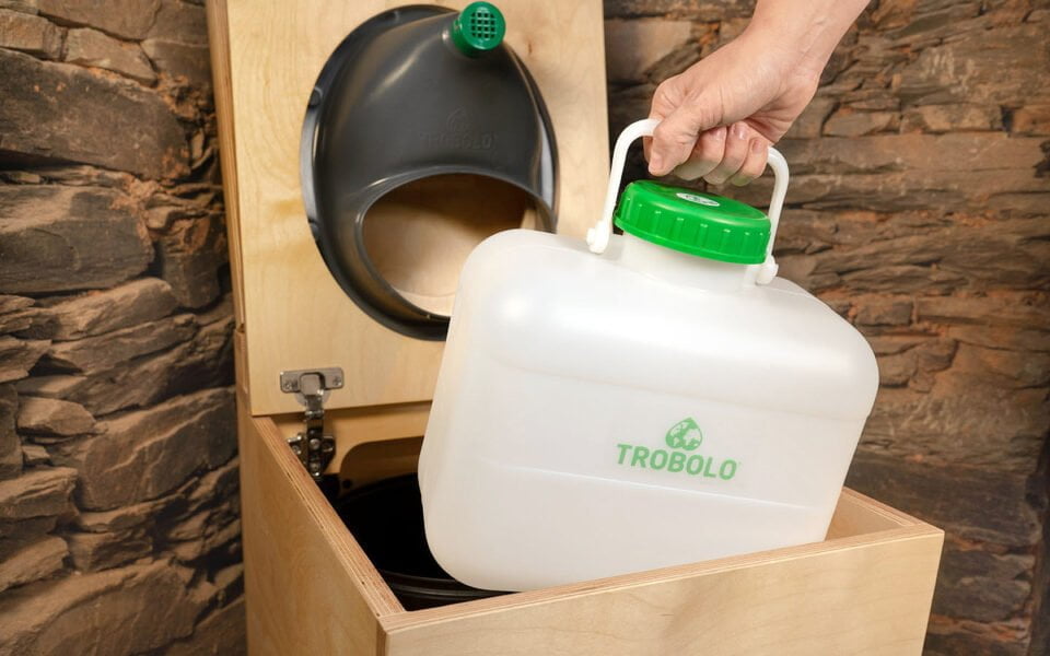 Der Flüssigkeitsbehälter einer Trockentrenntoilette wird aus dem Holzkorpus der Toilette herausgenommen zum Campingtoilette entleeren