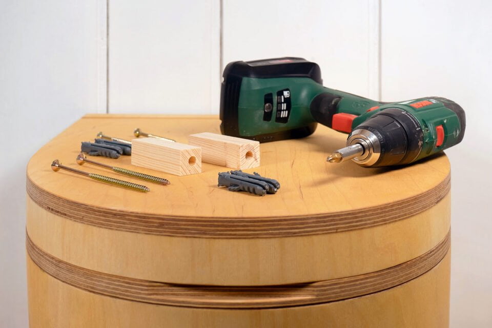 Werkzeug zum Trenntoilette selber bauen liegt auf dem Holzdeckel einer TROBOLO Trenntoilette
