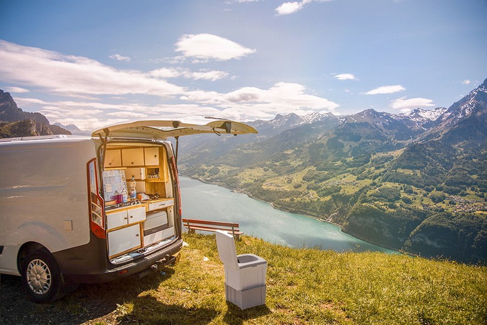 Campingtoilette TROBOLO WandaGO steht neben Van mit offener Kofferraum-Luke in der Natur